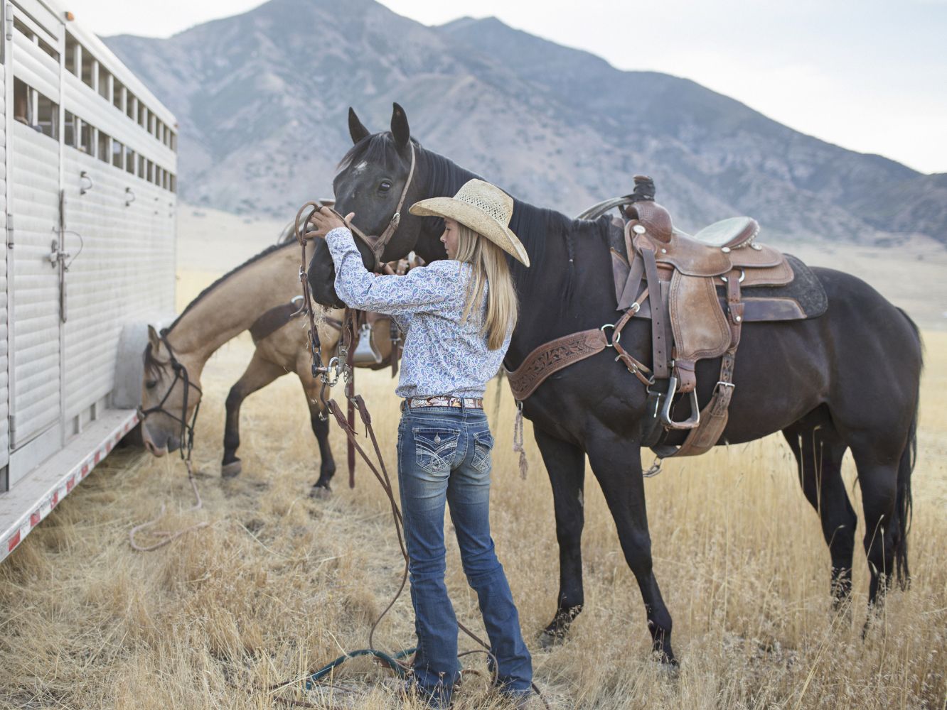 Young cowgirl preparing the horses for an event.